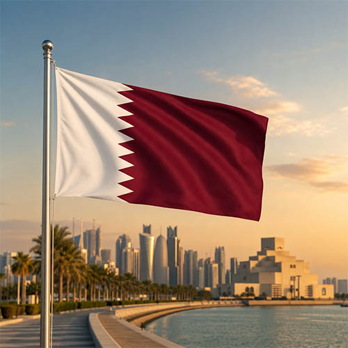 Flagge Katars vor der Skyline von Doha mit dem Museum of Islamic Art und der Corniche in warmer Abendstimmung.