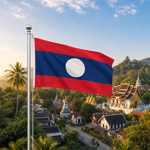 Laos Flagge - Bedeutung, Farben, Symbolik & Herkunft Flagge von Laos vor den buddhistischen Tempeln und der kolonialen Architektur von Luang Prabang, umgeben von tropischen Bäumen und Gartenanlagen bei goldenem Morgenlicht.