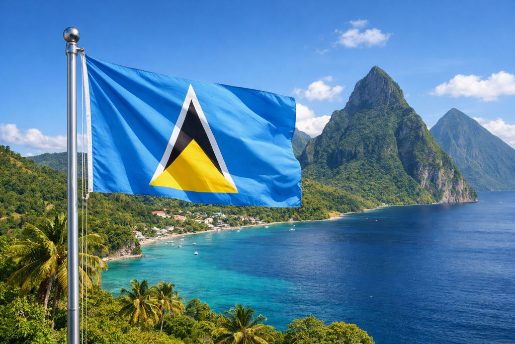 Nationalflagge von St. Lucia an einem Fahnenmast wehend; im Hintergrund tropische Karibiklandschaft mit türkisblauem Meer, bewaldeter Küste, Palmen und den markanten Pitons‑Bergen unter klarem Himmel, im 16:9‑Format